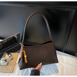 Detail of dark brown vintage leather shoulder bag with colorful beaded tassel pendant