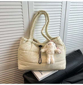 Detail of quilted puffer tote bag in cream white featuring cute plush rabbit keychain