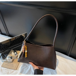 Detailed view of dark brown leather shoulder bag with vintage beaded fringe accessory