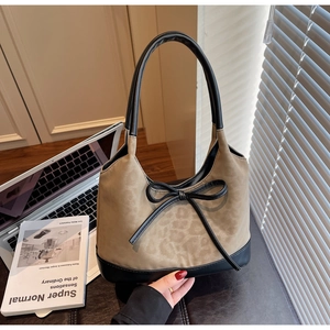 Close-up of leopard print tote bag with suede texture and black bow detail on desk