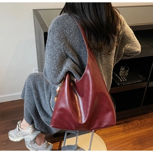 Close-up of a large burgundy tote bag with a smooth finish and spherical charm