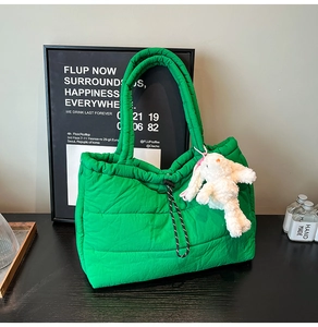 Detail of bright green quilted puffer tote bag with drawstring and rabbit charm