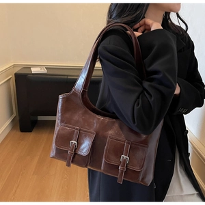 Detail of vintage brown tote bag with glossy finish and two front silver buckle pockets