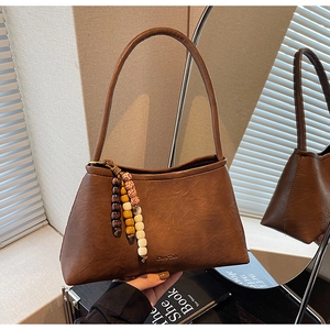 Detail of dark brown leather handbag featuring colorful bead charms and brand logo