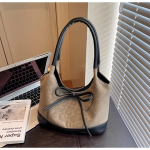 Detail of leopard print tote bag with black leather handles and delicate bow decoration
