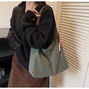 Détail du motif floral découpé au laser sur le sac fourre-tout vert avec doublure léopard