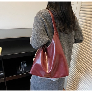 Detail of burgundy patent leather tote bag showing glossy texture and gold brand logo