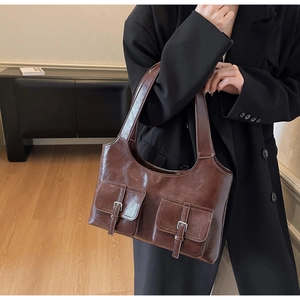 Detail of vintage brown leather underarm bag with dual pockets and silver metal buckles