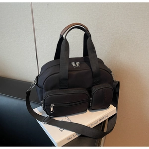 Detail showing two functional zipper pockets and reinforced handles of a black canvas bag