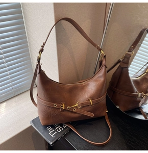 Dettaglio di una borsa hobo vintage marrone in ecopelle con cinturino ad occhielli metallici