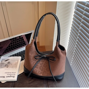 Detailed view of brown leopard print handbag with black leather bow and suede texture