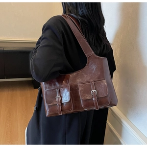 Detail view of retro brown faux leather tote bag with decorative pockets and metallic buckles