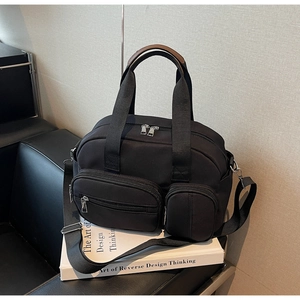 Close-up of black nylon multi-pocket Boston bag with leather handle and metal zippers