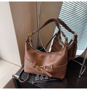 Dettaglio di una borsa hobo in pelle marrone scuro con fibbia in metallo dorato e zip