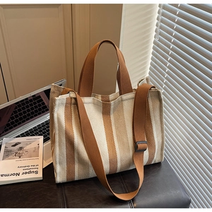 Detail of striped canvas tote bag showing adjustable wide shoulder strap and dual handles