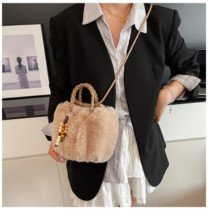 Detail der beigen Plüsch-Eimertasche mit Holzperlen-Anhänger und gewebtem Griff