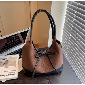 Detail of a brown leopard print suede shoulder bag with a delicate black leather bow accent
