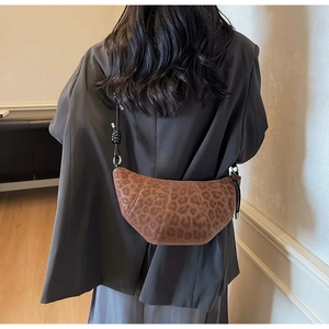 Fashionable leopard print crescent bag with adjustable strap worn on the shoulder