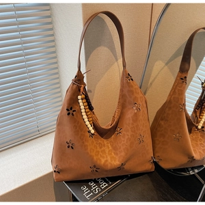 Détails de motifs découpés et gaufrage léopard sur sac cabas en daim marron foncé
