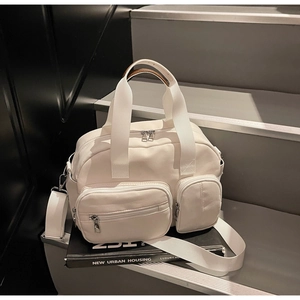Detail of white nylon tote bag with dual zippers and leather handle on steps