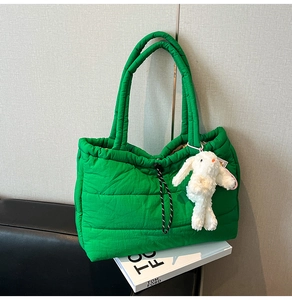 Detail of green quilted puffer tote bag featuring drawstring closure and white rabbit charm