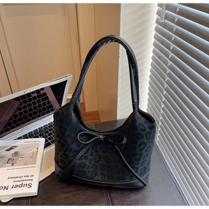 Detailed view of black leopard print shoulder bag with bow and sleek suede texture