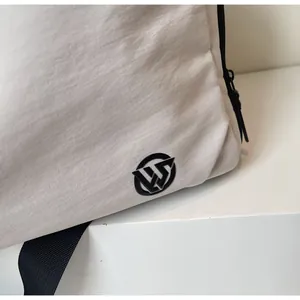 Close-up of white nylon travel bag showing black logo detail and textured fabric