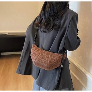 Detail of leopard print suede croissant bag showing curved stitching and crossbody strap