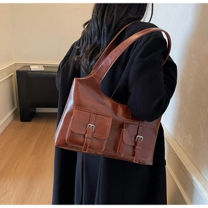 Detail view of retro brown faux leather tote with dual front pockets and metal buckles