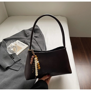 Detail of dark brown leather underarm bag with vintage texture and colorful wooden beads