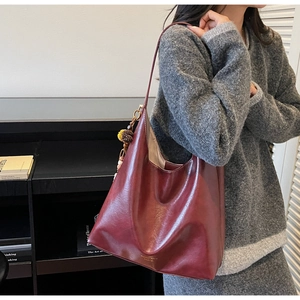 Detail view of burgundy leather tote bag with bohemian tassel and gold brand text