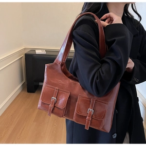 Close-up of retro reddish-brown tote bag with dual front pockets and silver buckle accents