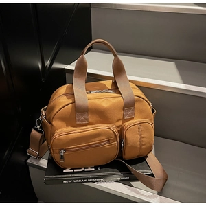 Detail view of caramel nylon tote with dual front pockets and adjustable crossbody strap