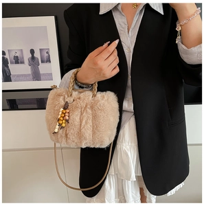 Detail der flauschigen beigen Beuteltasche mit geflochtenem Griff und Perlenanhänger