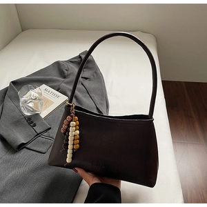 Detail of vintage dark brown leather underarm bag with long beaded tassel charm