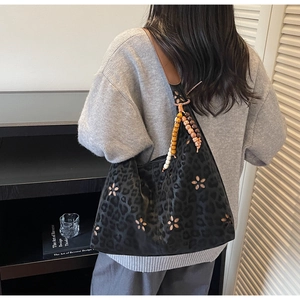 Détail du sac à bandoulière noir imprimé léopard avec découpes de fleurs et perles