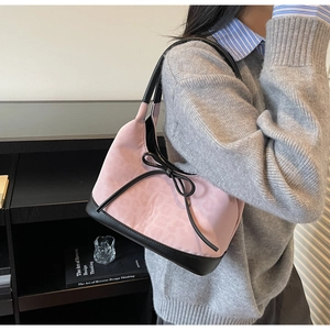 Close-up of pink and black tote bag featuring a large bow and faux suede texture