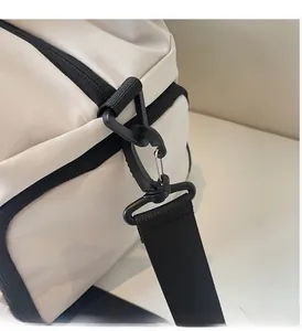 Detail of durable black detachable swivel hook and nylon strap on a beige travel bag