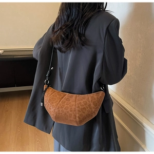 Detail view of a vintage leopard print croissant bag with textured suede finish and strap knot