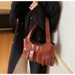 Detail of caramel faux wax leather tote bag with front pockets and metallic buckles