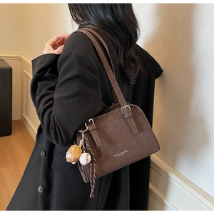 Macro view of a dark brown retro shoulder bag with matte texture and baseball charm