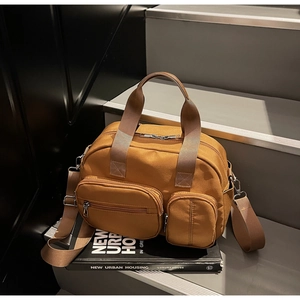 Close-up of tan canvas tote bag with multi-pocket design and adjustable strap