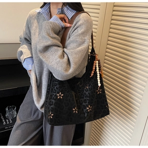 Détail du sac cabas ajouré noir avec imprimé léopard et pompon perlé sur l'épaule