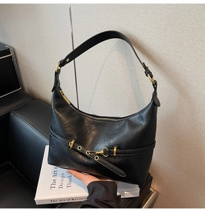 Dettaglio borsa a mezzaluna nera in similpelle con finiture dorate e chiusura a zip