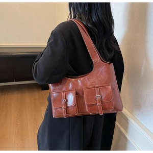 Detail of vintage brown tote bag with oily leather finish and two front buckle pockets