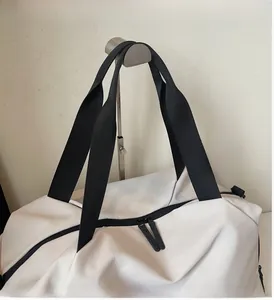 Detail of sturdy black woven handles and metal zipper on cream white nylon travel bag