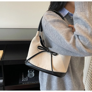 Detail of a chic cream and black bow shoulder bag styled with an autumn knit sweater