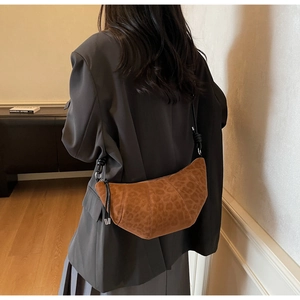 Detail of a brown leopard print croissant bag showing soft suede texture and adjustable strap