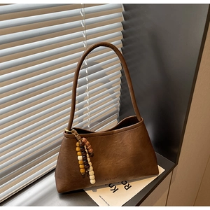 Detailed close-up of dark brown PU leather shoulder bag with colorful wooden bead charm