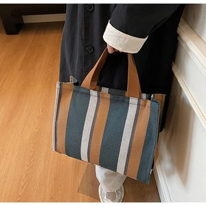 Detailed close-up of a large striped canvas tote bag with brown woven handles